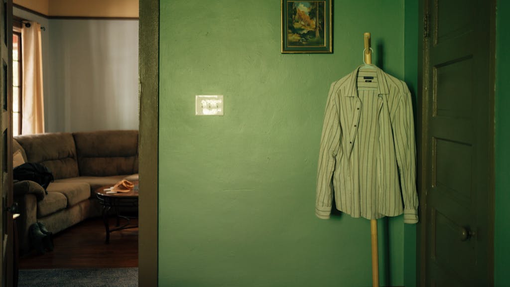 A minimalist interior shot featuring a striped shirt hanging on a green wall in Gainesville, FL.