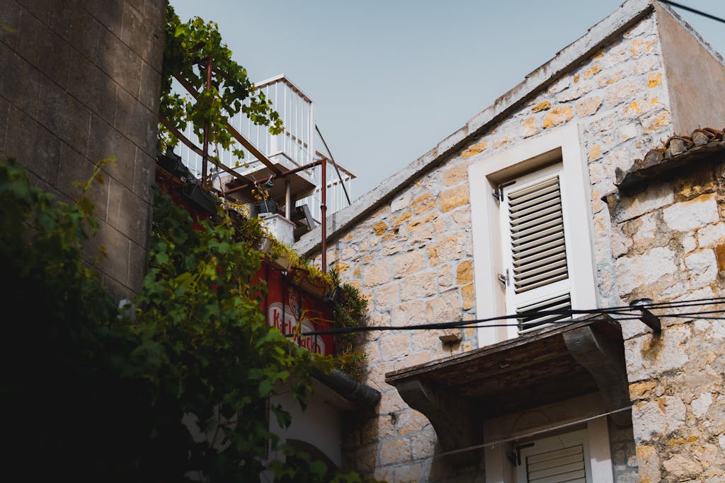 A rustic stone building with vines and a shuttered window, evoking traditional architecture.
