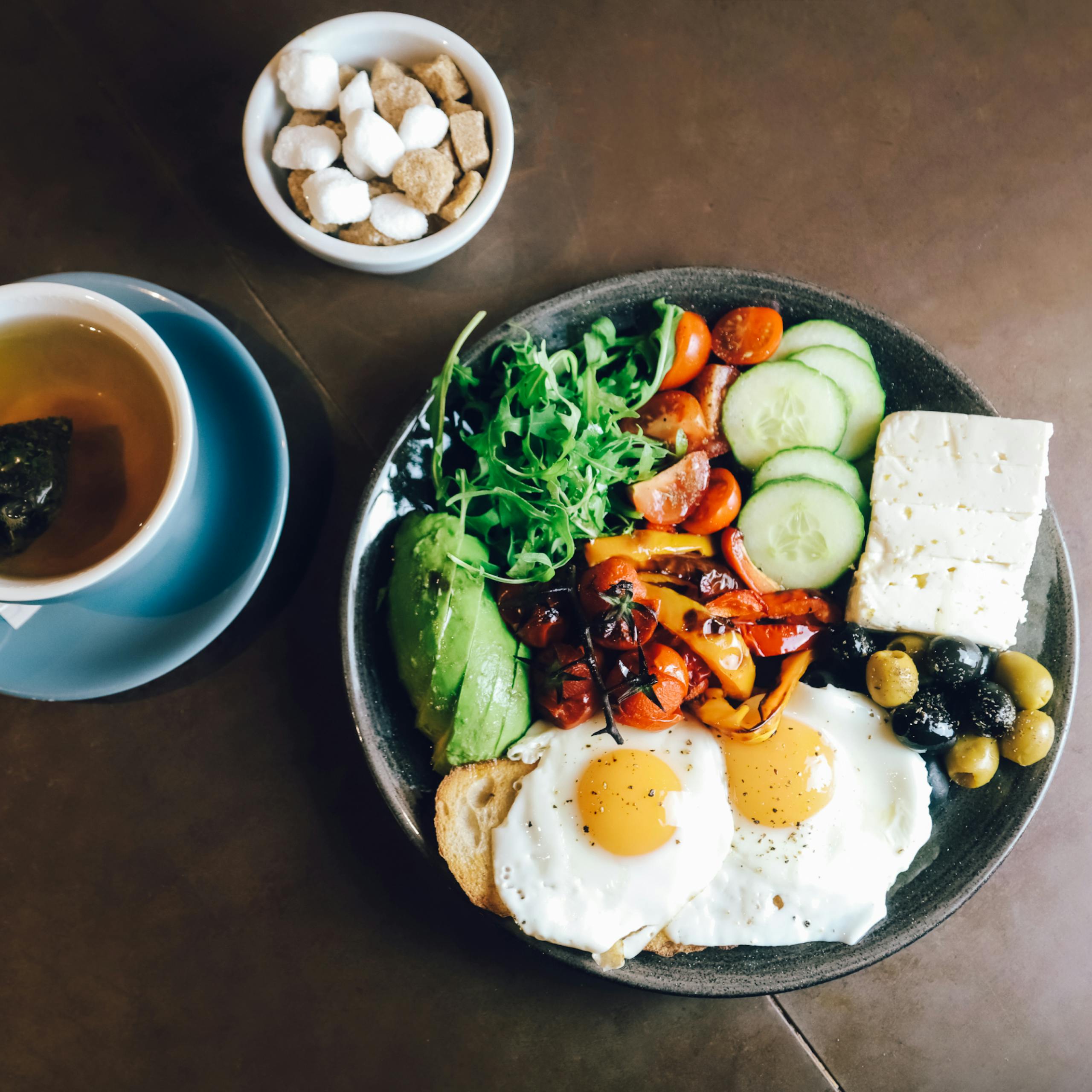 A scrumptious Mediterranean breakfast with eggs, olives, veggies, and tea.