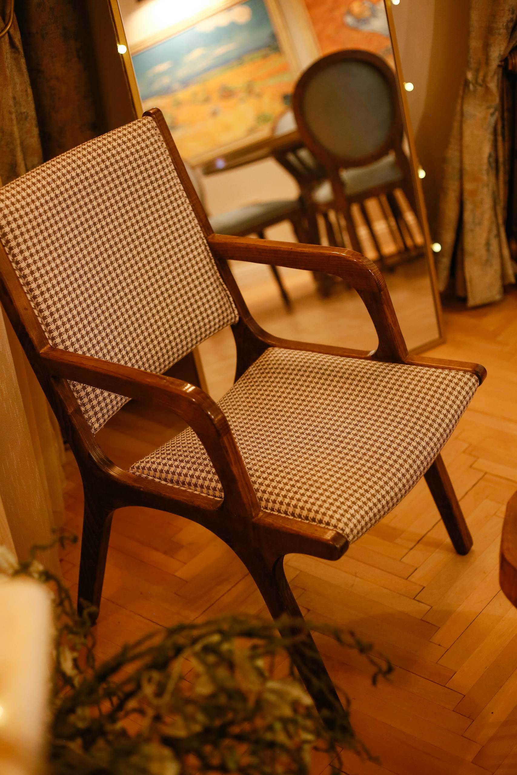 A stylish wooden chair with checkered upholstery in a warmly lit indoor space.
