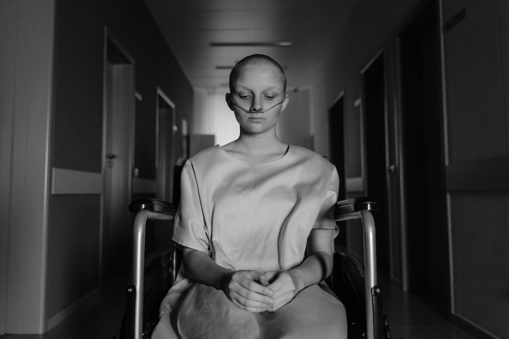 A woman in a wheelchair, deep in thought, in a hospital corridor.