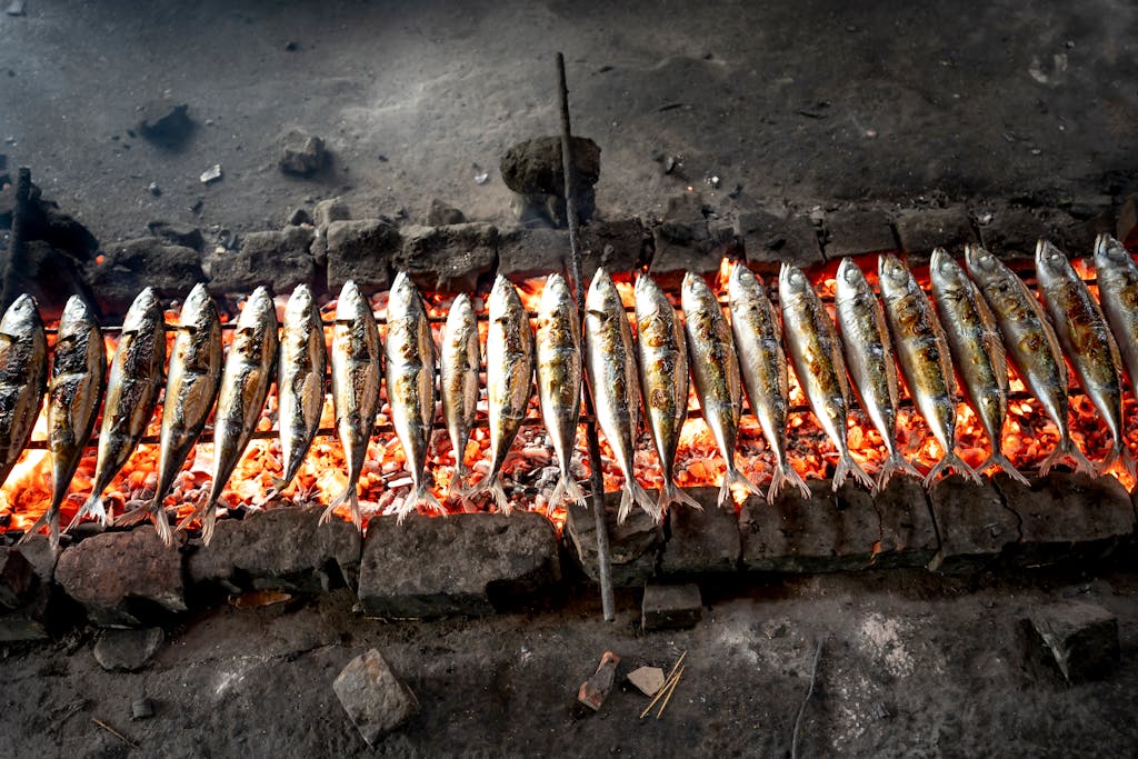 Array of fish grilling on an open fire pit for traditional cooking.