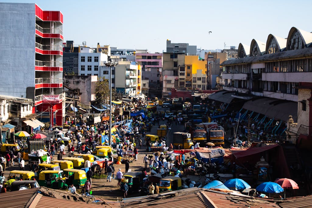 Bustling street scene in Bengaluru, India with colorful vehicles and vibrant market activity.
