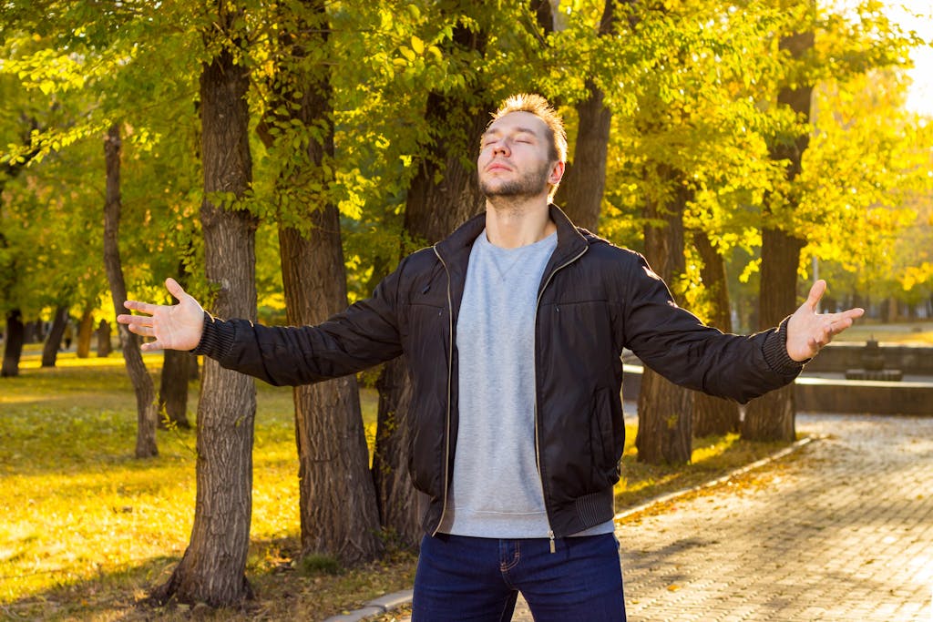 Caucasian man with eyes closed embracing nature in an autumn park.