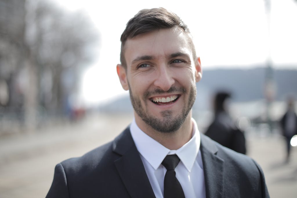 Cheerful businessman outdoors in formal attire, radiating confidence and approachability.