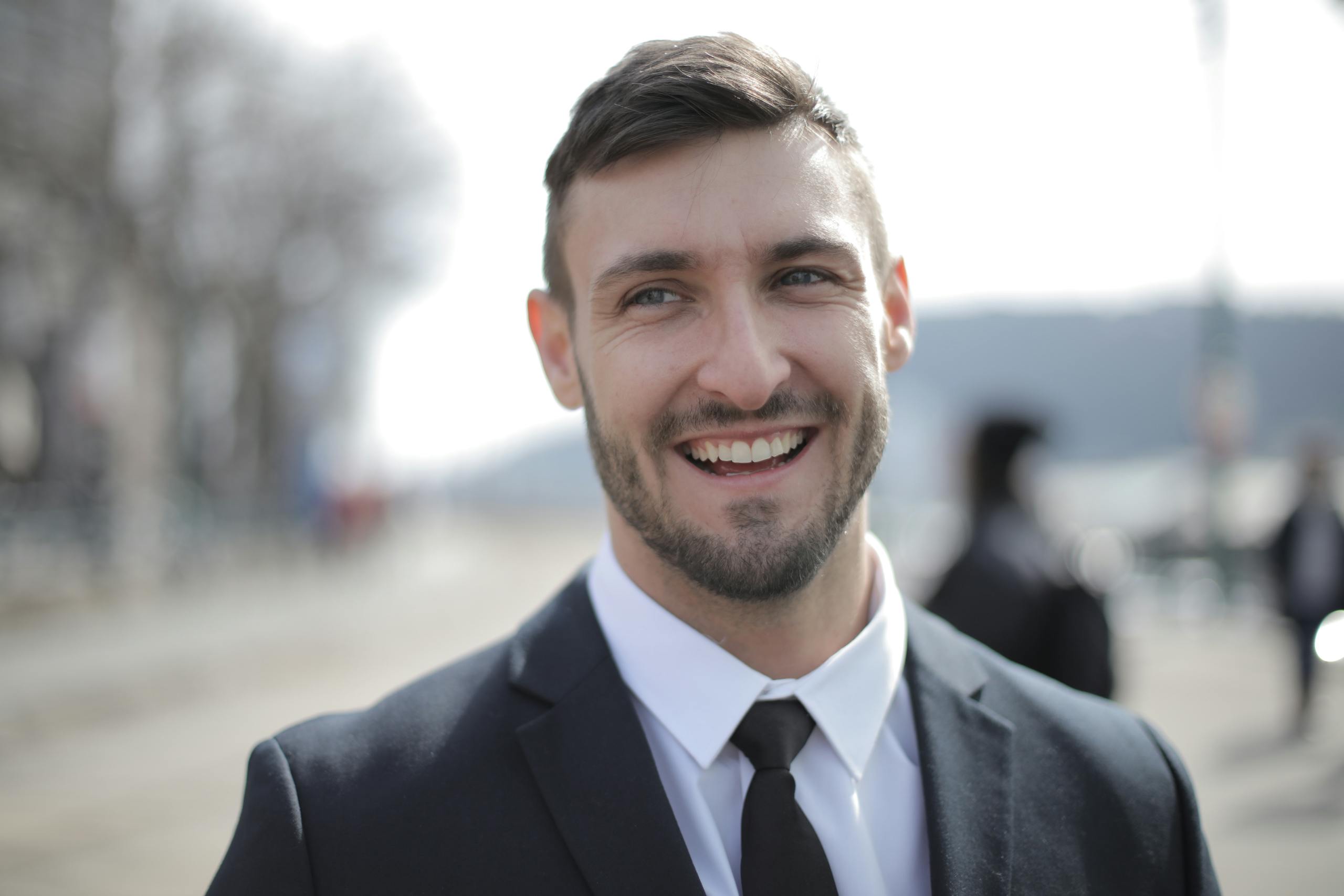 Cheerful businessman outdoors in formal attire, radiating confidence and approachability.