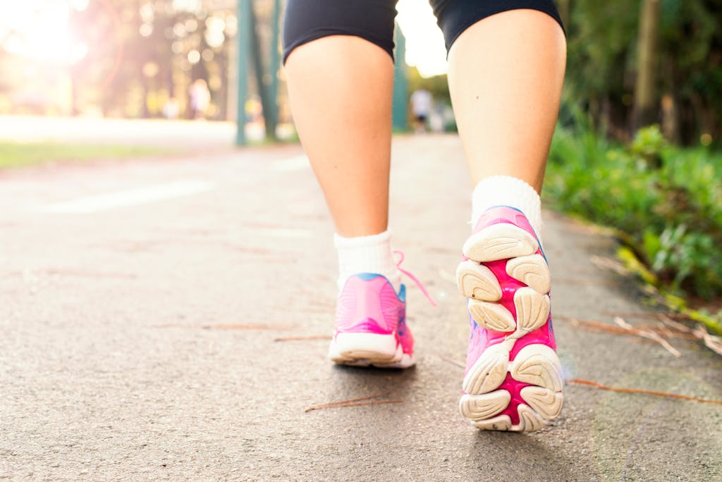 Ignoring These 10 Healthy Habits Could Be Shortening Your Life 1 Close-up of a woman walking on a path in pink sneakers, embracing fitness and an active lifestyle.