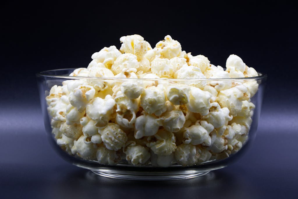 Close-up of freshly popped popcorn in a clear glass bowl, perfect snack idea.