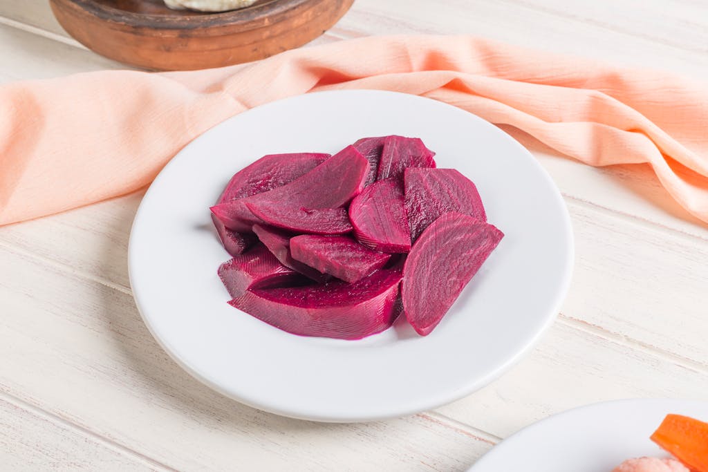 Close-up of vibrant beet slices on a white plate, emphasizing freshness and color.