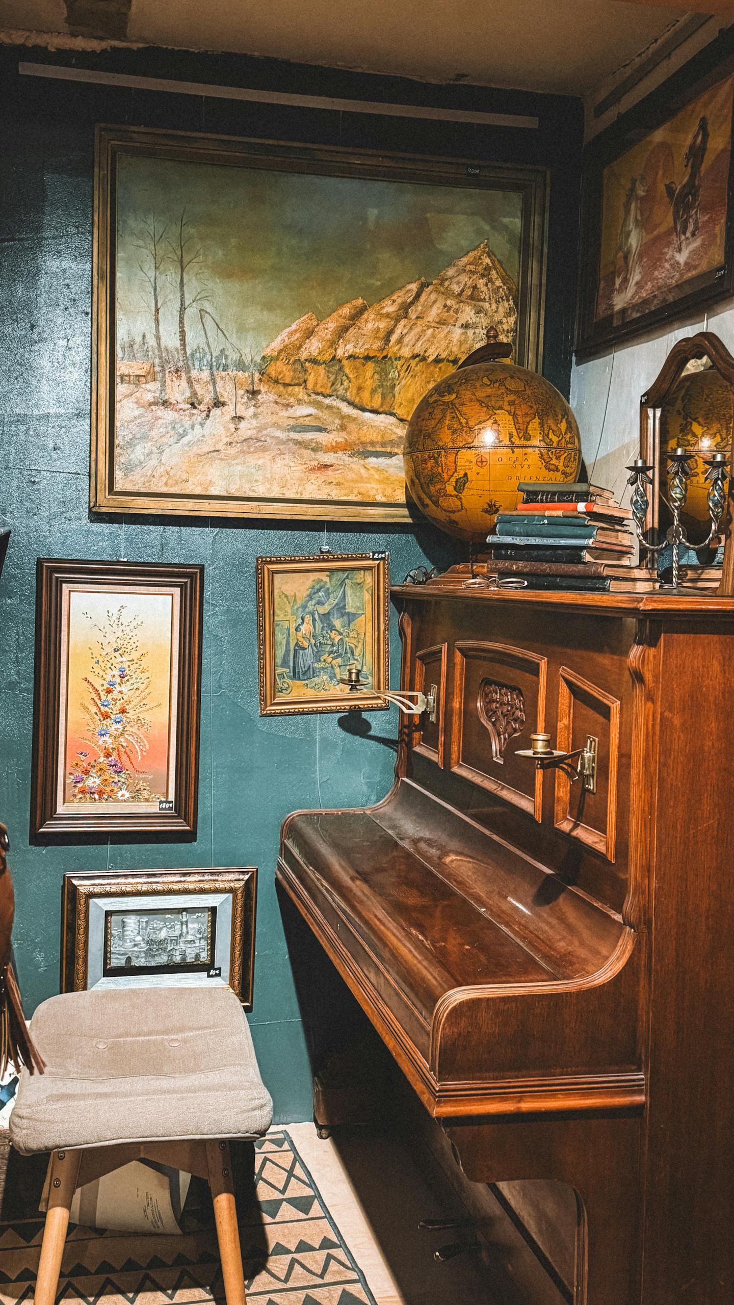 Cozy vintage room featuring a wooden piano, art, and globe.