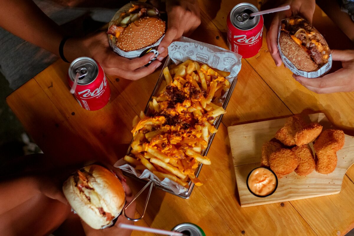 Delicious fast food spread featuring burgers, fries, nuggets, and drinks on a wooden table.