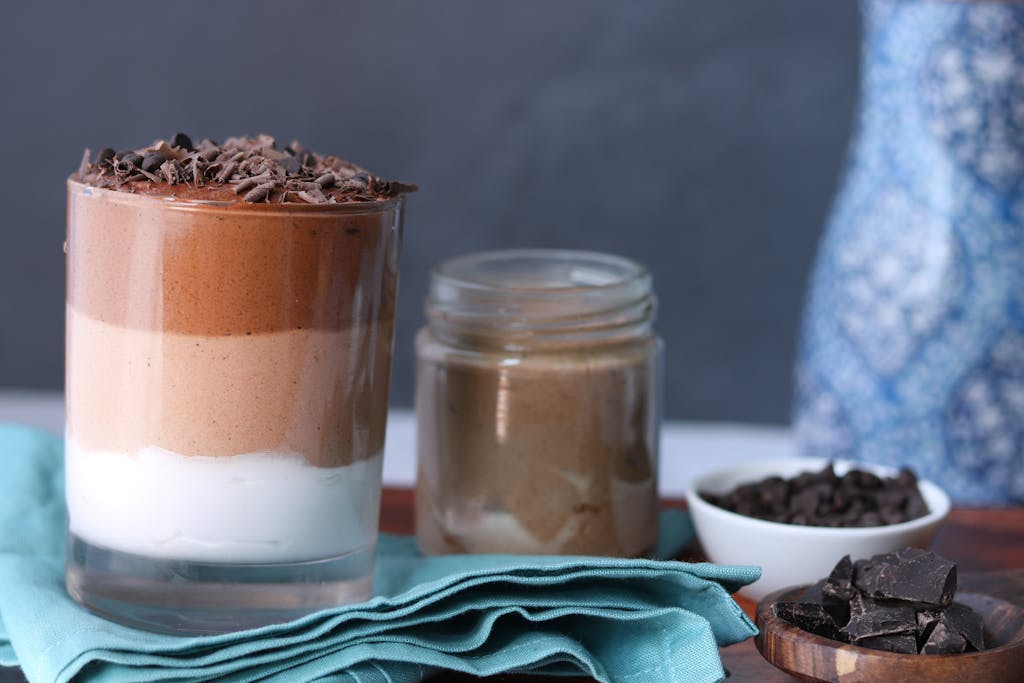 Delicious layered chocolate mousse in a clear glass with chocolate shavings, next to ingredients.