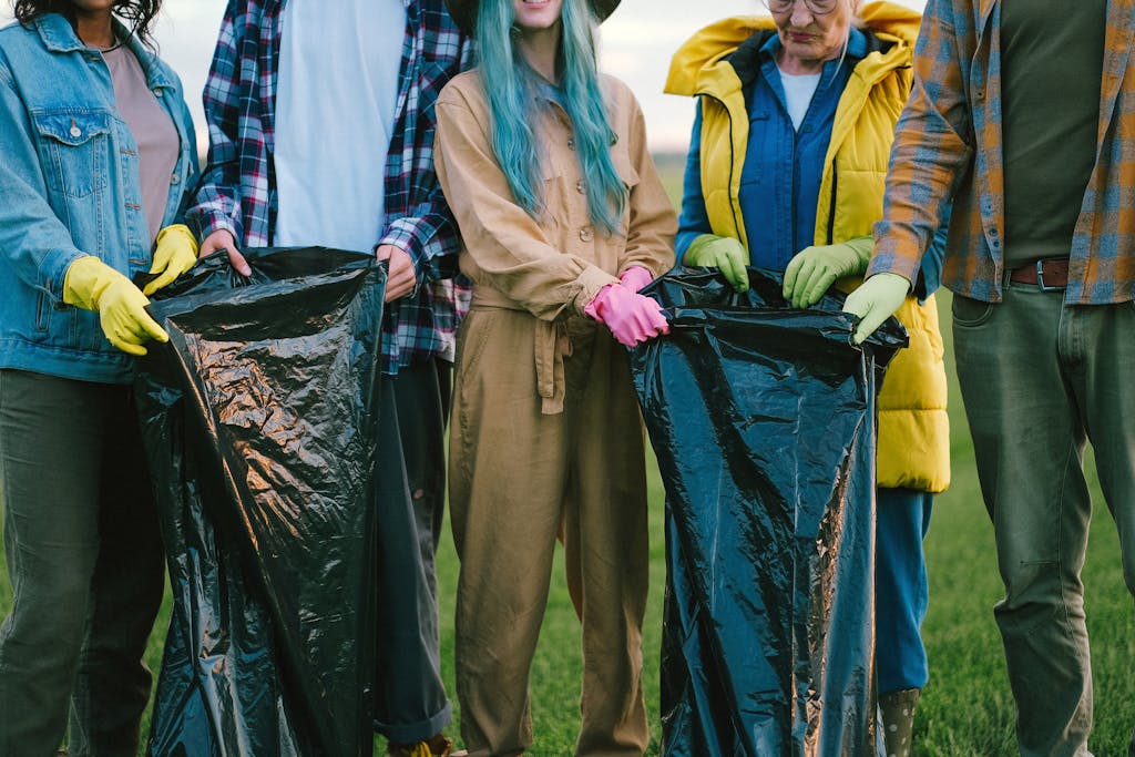 If You Ignore These 8 Things as a Retiree, You Will Be Isolated and Lost 3 Diverse volunteers cleaning up a field, holding large trash bags and wearing gloves.