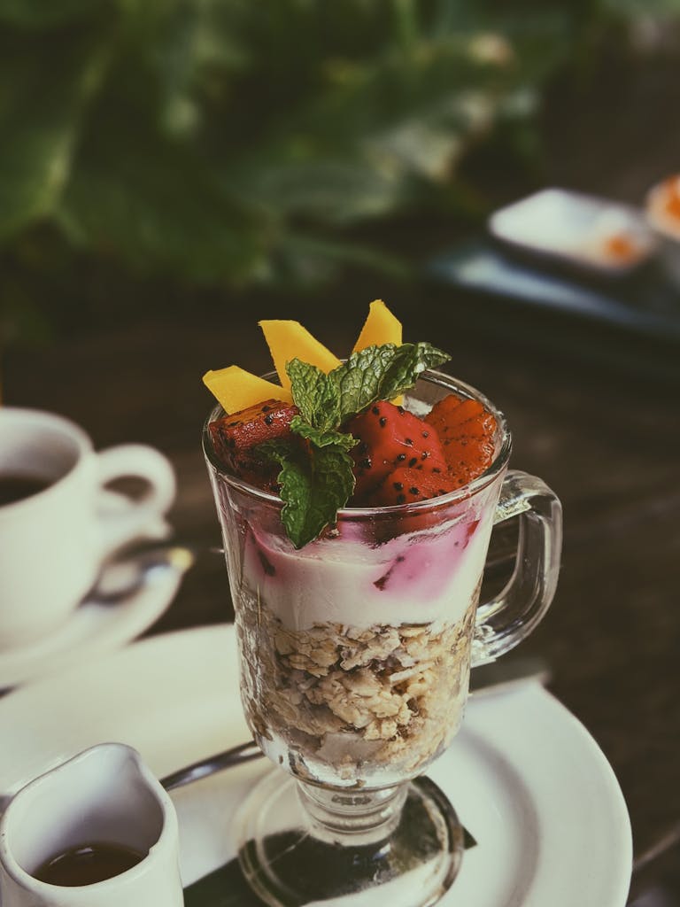 Enjoy a refreshing fruit yogurt parfait with granola and fresh mint, perfect for a healthy tropical snack.