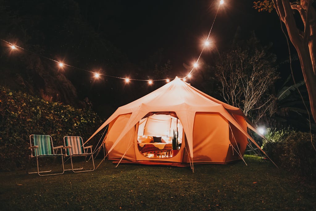 Explore a nighttime campsite with a cozy illuminated tent, perfect for a serene outdoor escape.