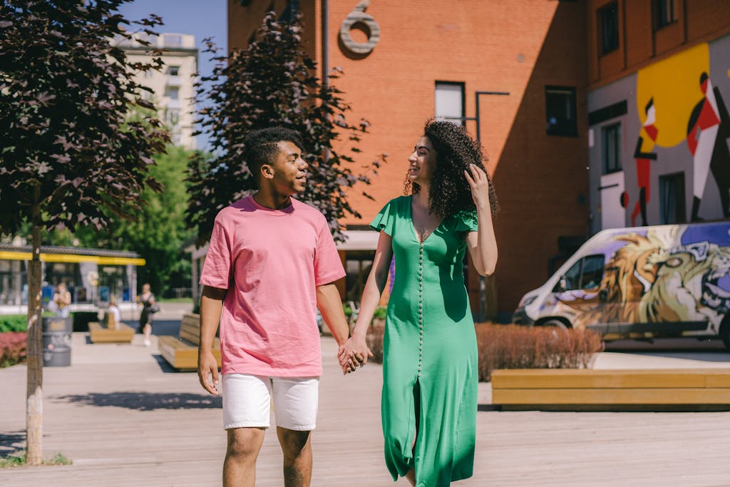 Happy interracial couple walking hand in hand in a vibrant city setting with colorful murals.