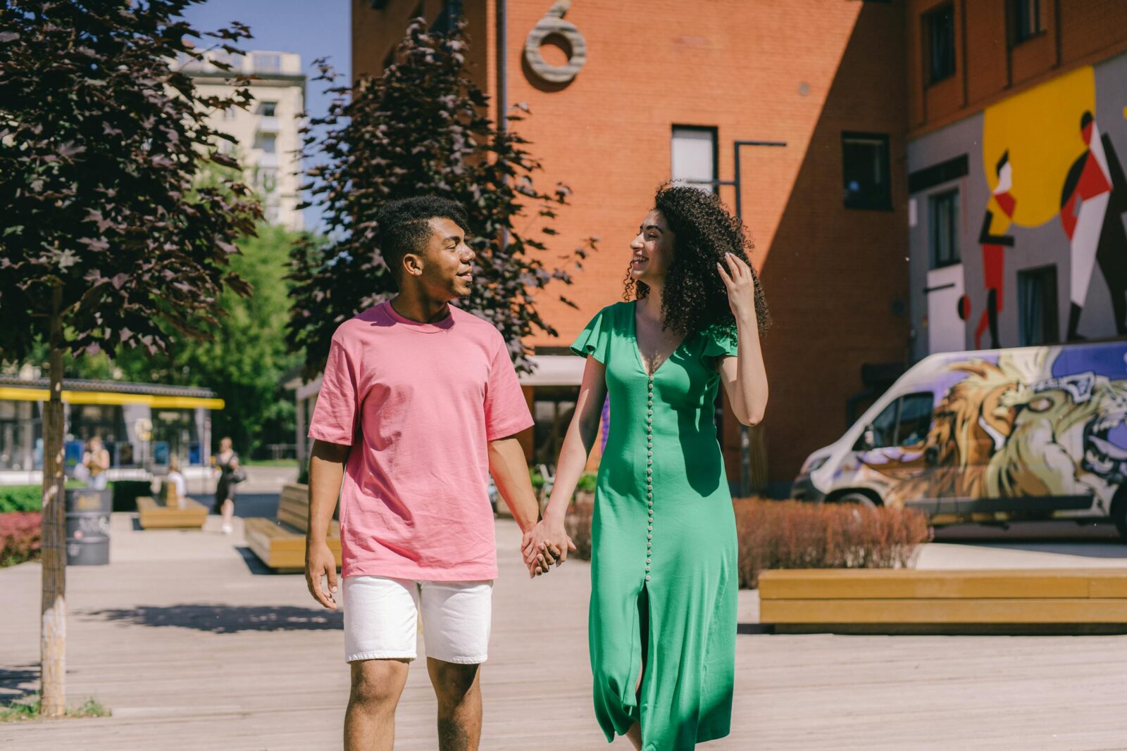 Happy interracial couple walking hand in hand in a vibrant city setting with colorful murals.
