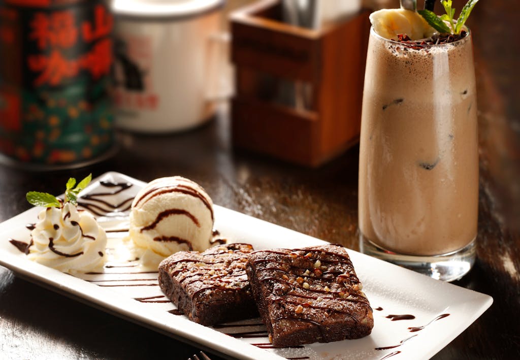Indulge in rich brownies with ice cream and iced coffee, a perfect dessert combo.