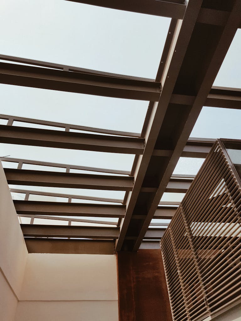 Low angle view of a modern indoor structure featuring a sleek skylight and metal beams.