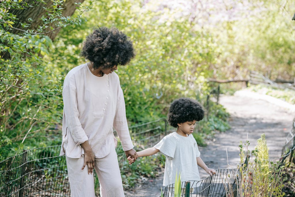 Mother and daughter enjoying a walk in a sunny park, holding hands amidst nature.