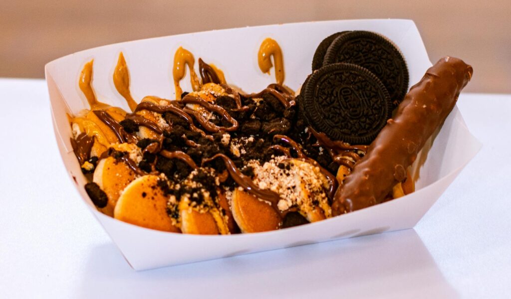 Mouthwatering dessert with waffles, cookies, and chocolate bar in a paper tray.