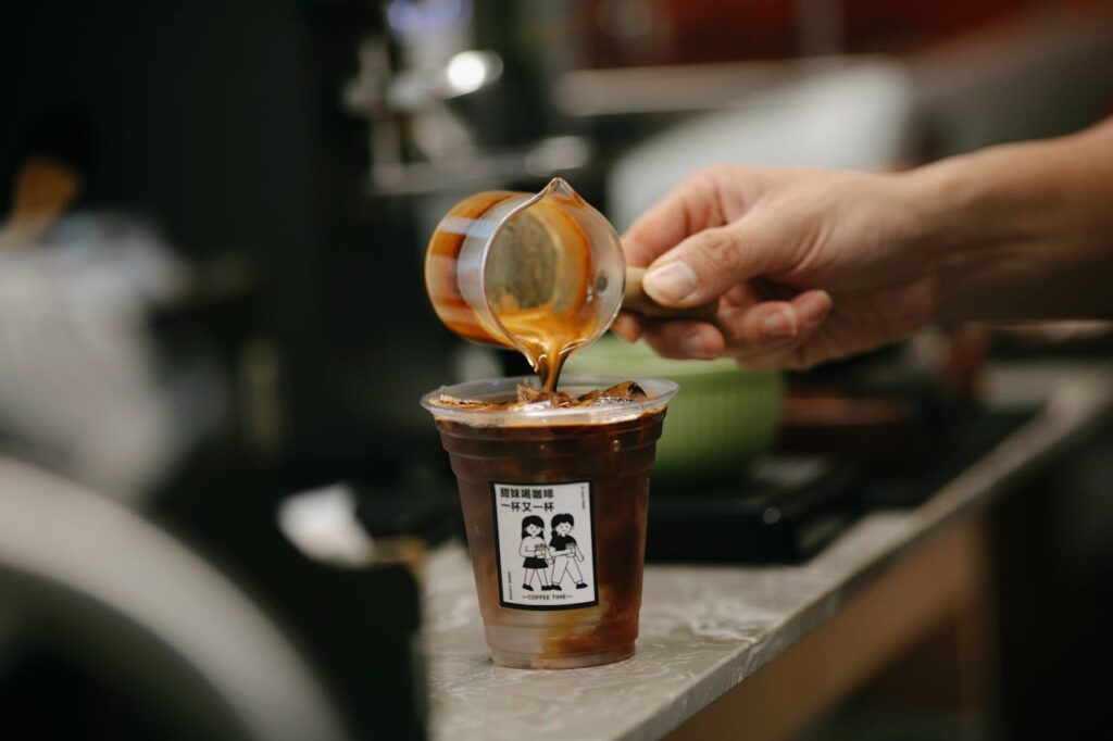 /pouring-caramel-syrup-over-iced-coffee-in-cafe