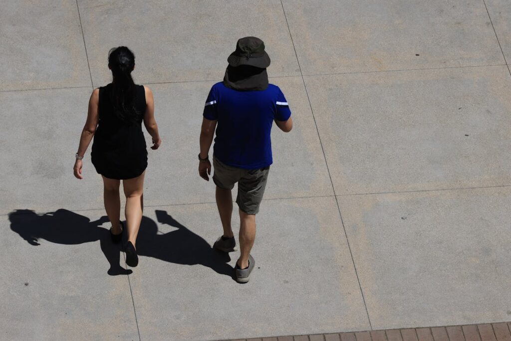 woman-and-man-walking-on-sunlit-pavement