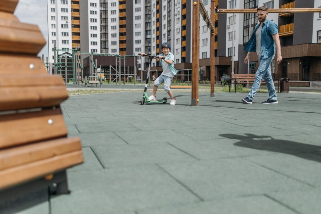 a-boy-riding-a-scooter-in-the-park-with-his-father-