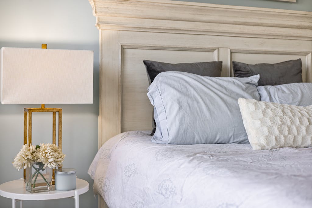 6 Worst Places You Should Never Keep Your Phone 4 Stylish bedroom interior featuring a comfy bed, decorative pillows, and a modern lamp on a side table.
