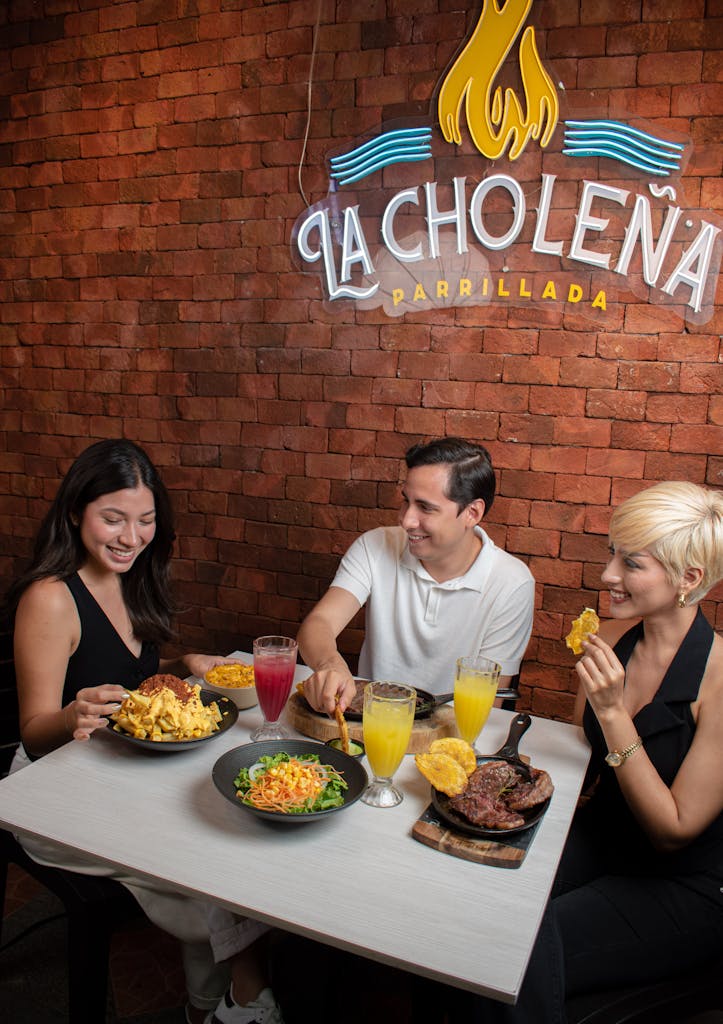 Three friends enjoying a meal together at La Choleña Parrillada restaurant. Vibrant and lively atmosphere.