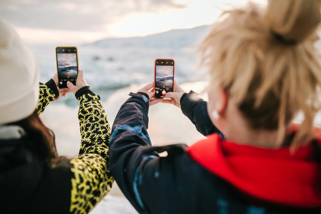 Two travelers take smartphone photos of a beautiful landscape while enjoying an outdoor adventure.