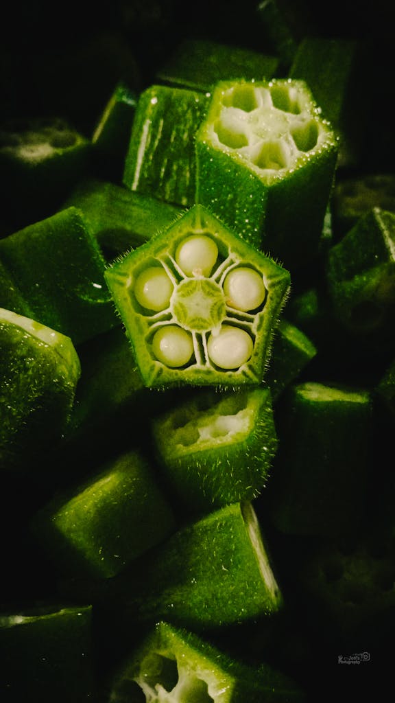 Vibrant close-up of sliced green okra, highlighting its fresh texture and intricate seed pattern.