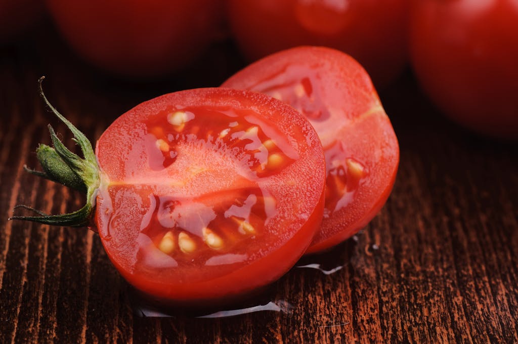 Vivid close-up of juicy sliced tomatoes showcasing their freshness on a wooden background.