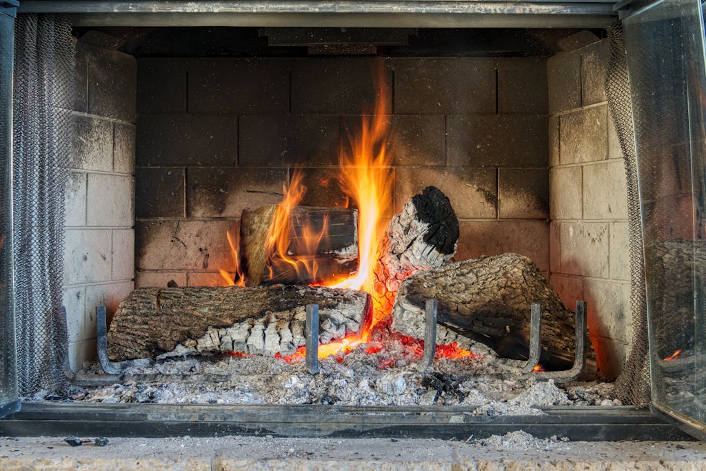 Warm and cozy fireplace with logs burning bright, providing warmth indoors.