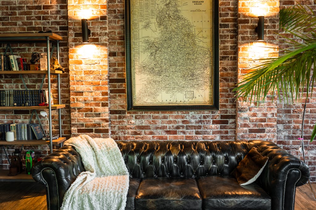 Warm and inviting living room with a vintage leather sofa against a brick wall and map decor.