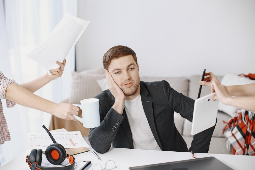 A businessman overwhelmed by tasks in a modern office setting, depicting multitasking and stress.