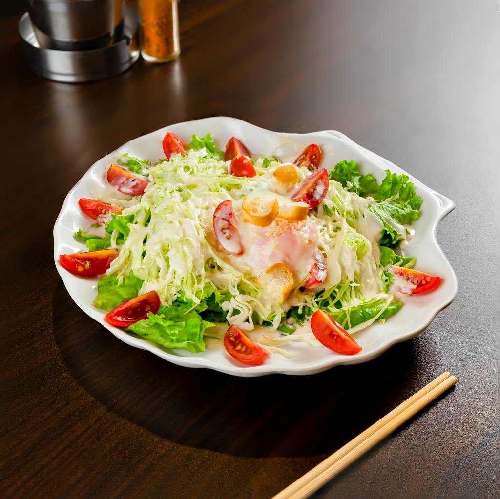 A close-up of a fresh vegetable salad with lettuce, tomatoes, and croutons on a white plate.