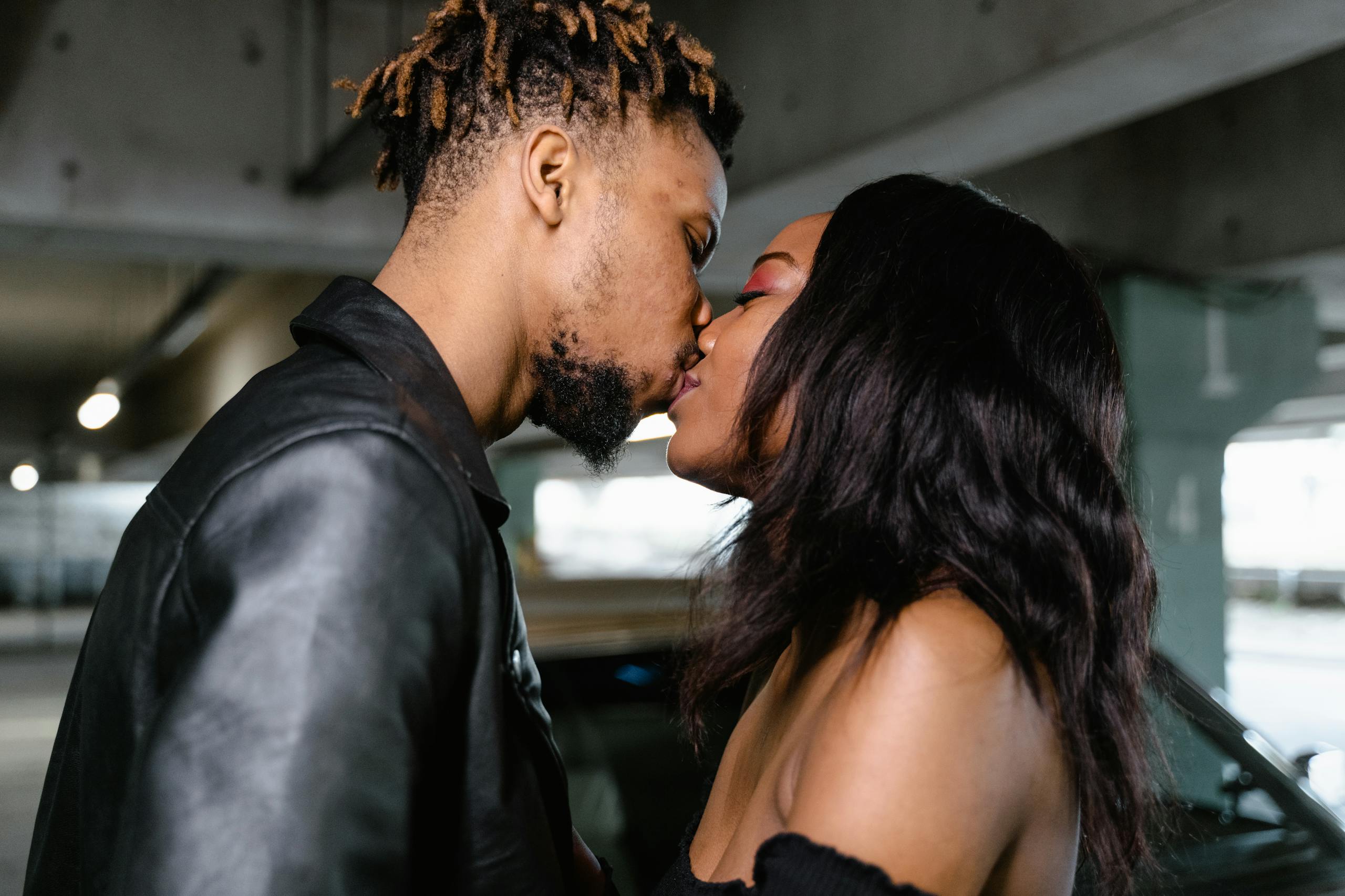 A close-up of an interracial couple sharing an intimate moment and kiss indoors.