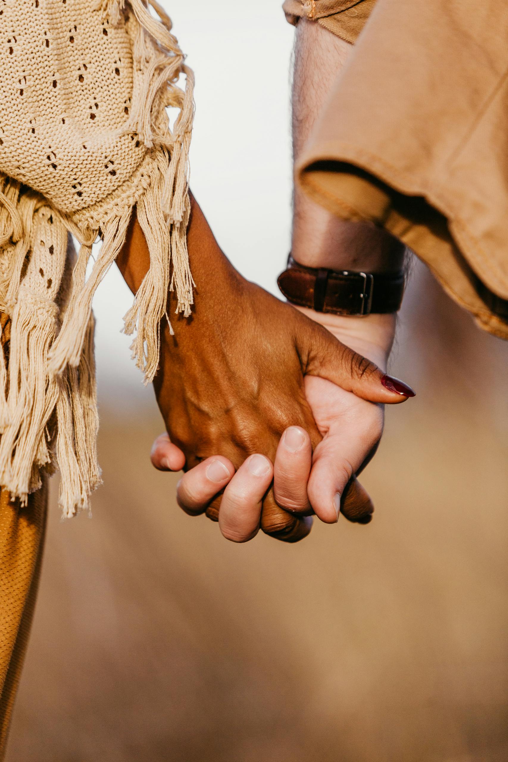 A close-up shot of a diverse couple holding hands, symbolizing unity and love.