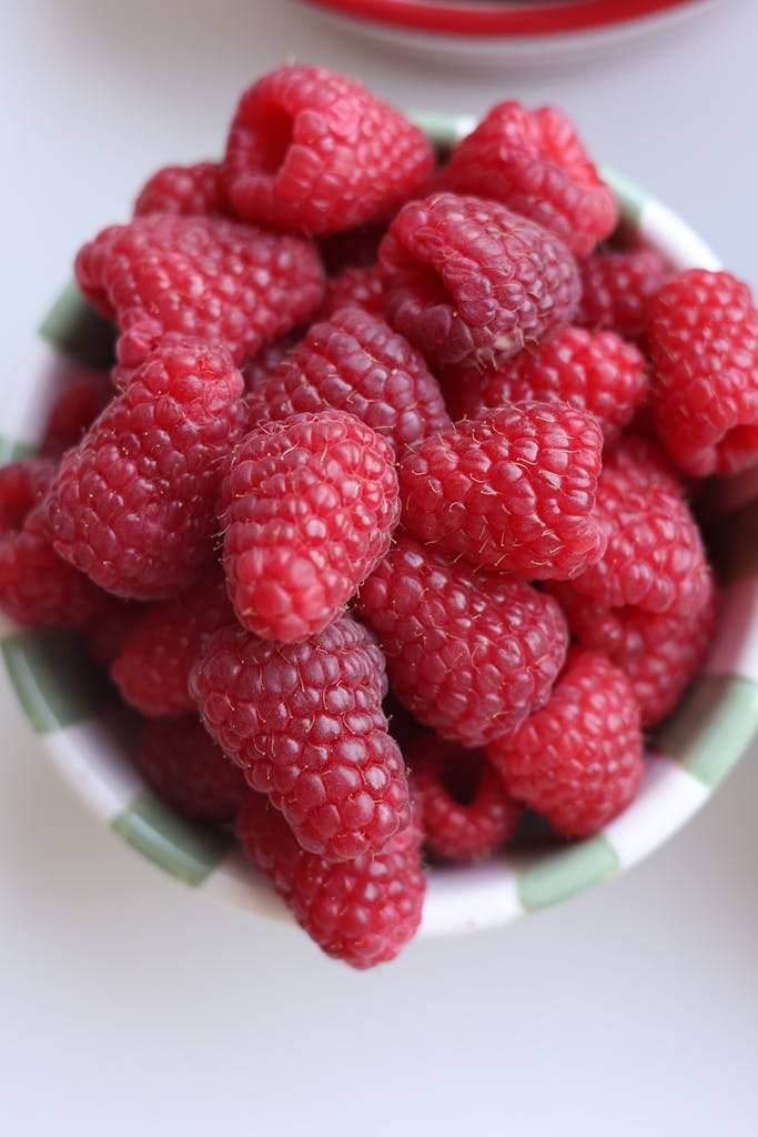 A close-up shot of fresh, ripe raspberries in a ceramic bowl, perfect for healthy eating concepts.