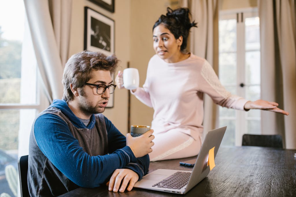 A couple having an argument at home, with a laptop on the table.