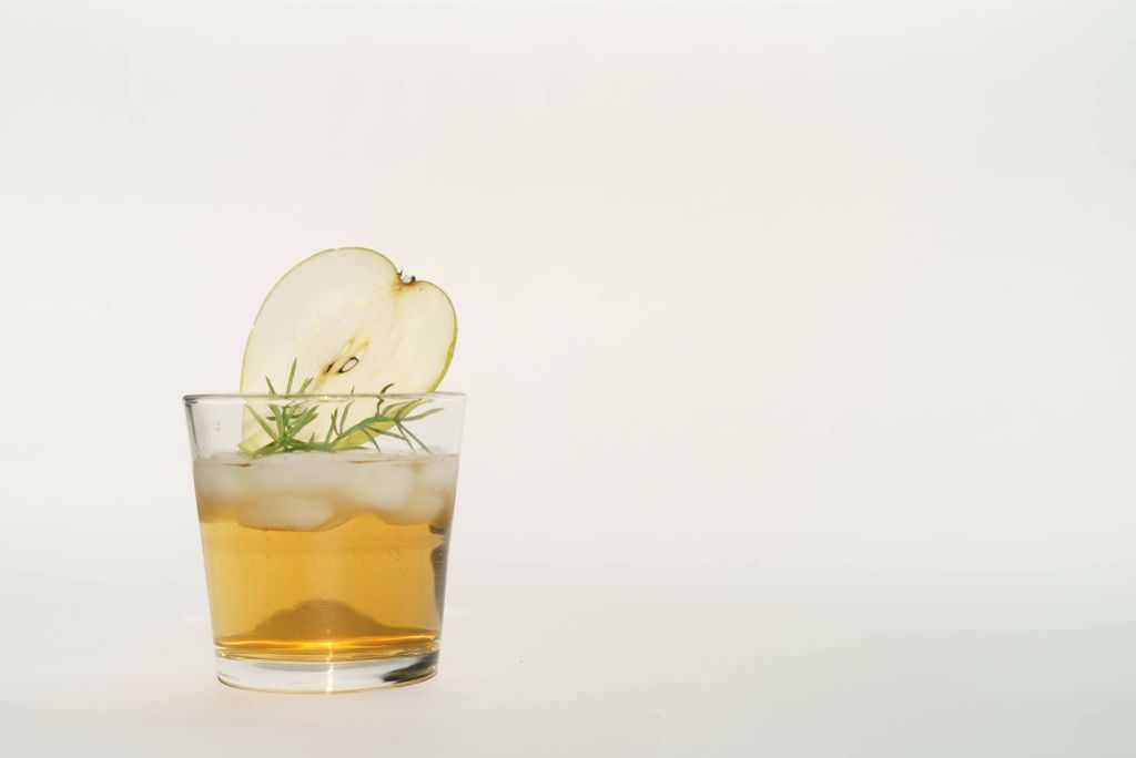 A crisp cocktail with apple garnish and ice in a clear glass, perfect for a refreshing drink.