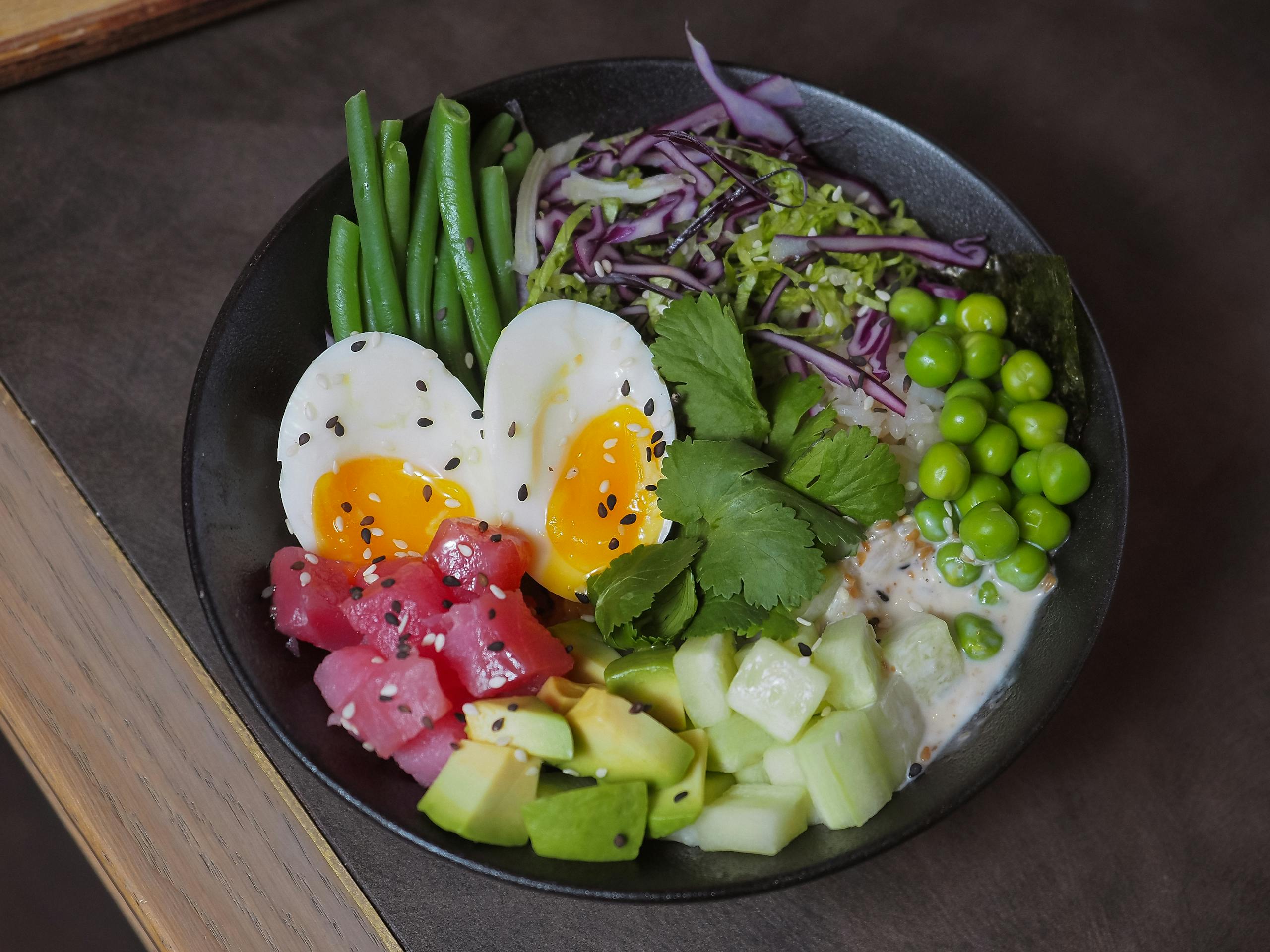 A delicious and colorful poke bowl featuring eggs, vegetables, and fresh produce, perfect for a healthy meal.