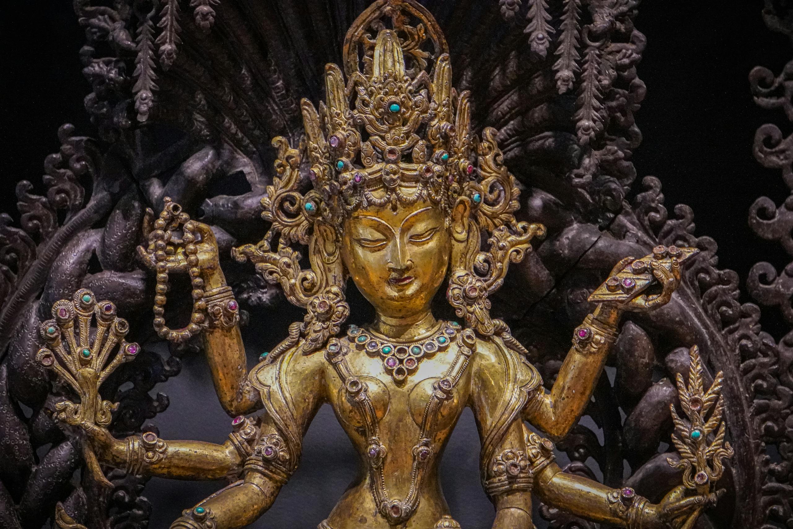 A detailed gold statue of a Hindu goddess adorned with jewels, showcasing intricate craftsmanship.
