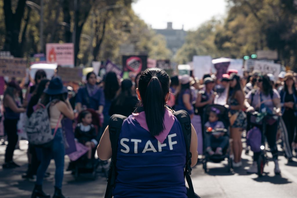 A diverse group of people gather for a rally with placards in Mexico City.