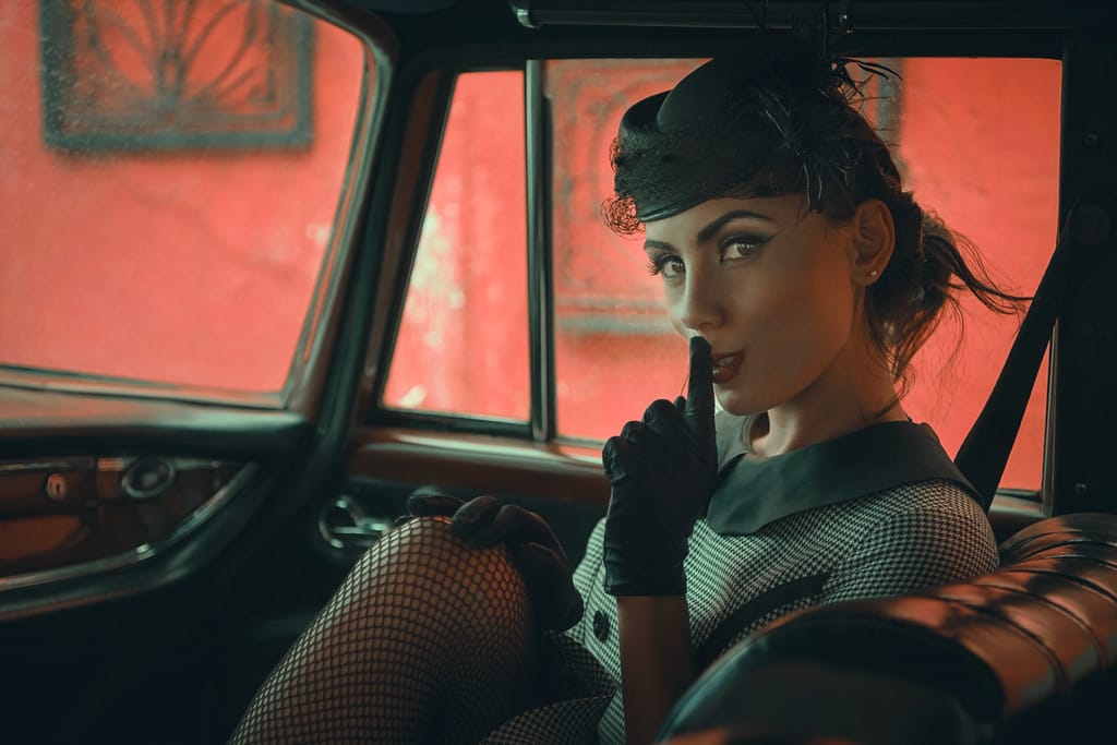 A fashionable woman in a vintage car, exuding elegance and glamour.