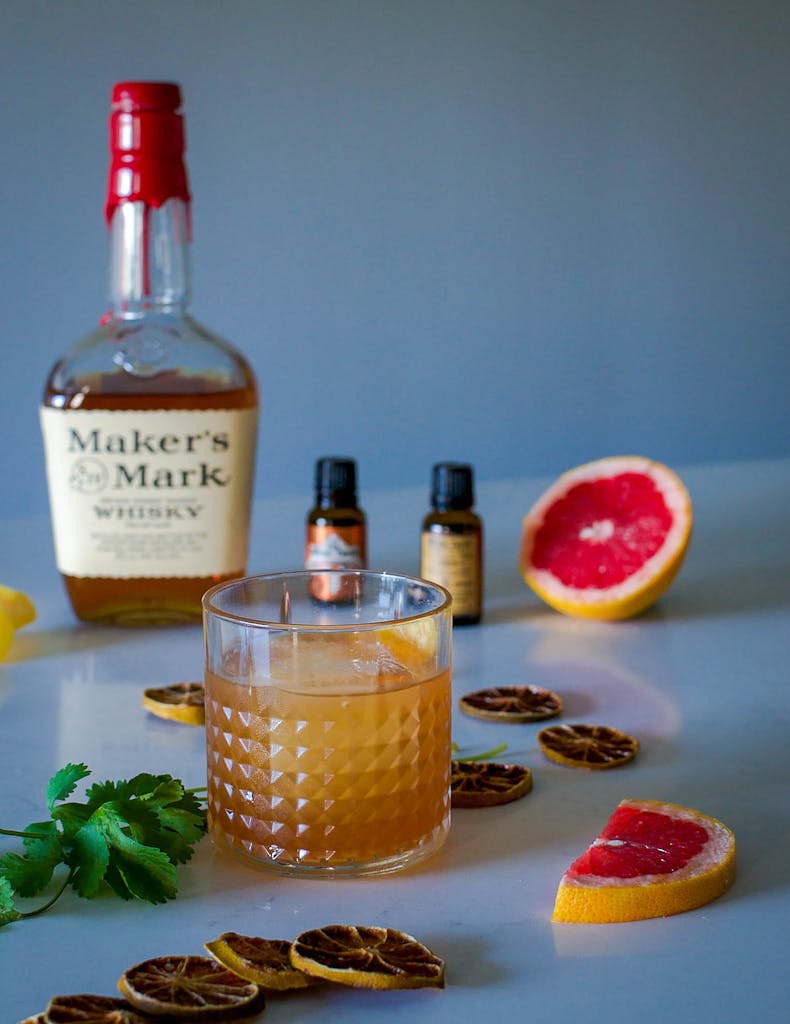 A glass of whiskey cocktail with dried and fresh citrus, perfect for a refreshing drink.