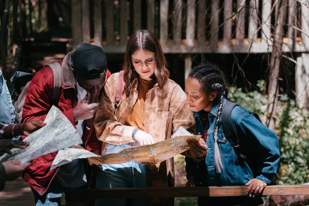 A group of young friends studying a map outdoors, planning an adventure.