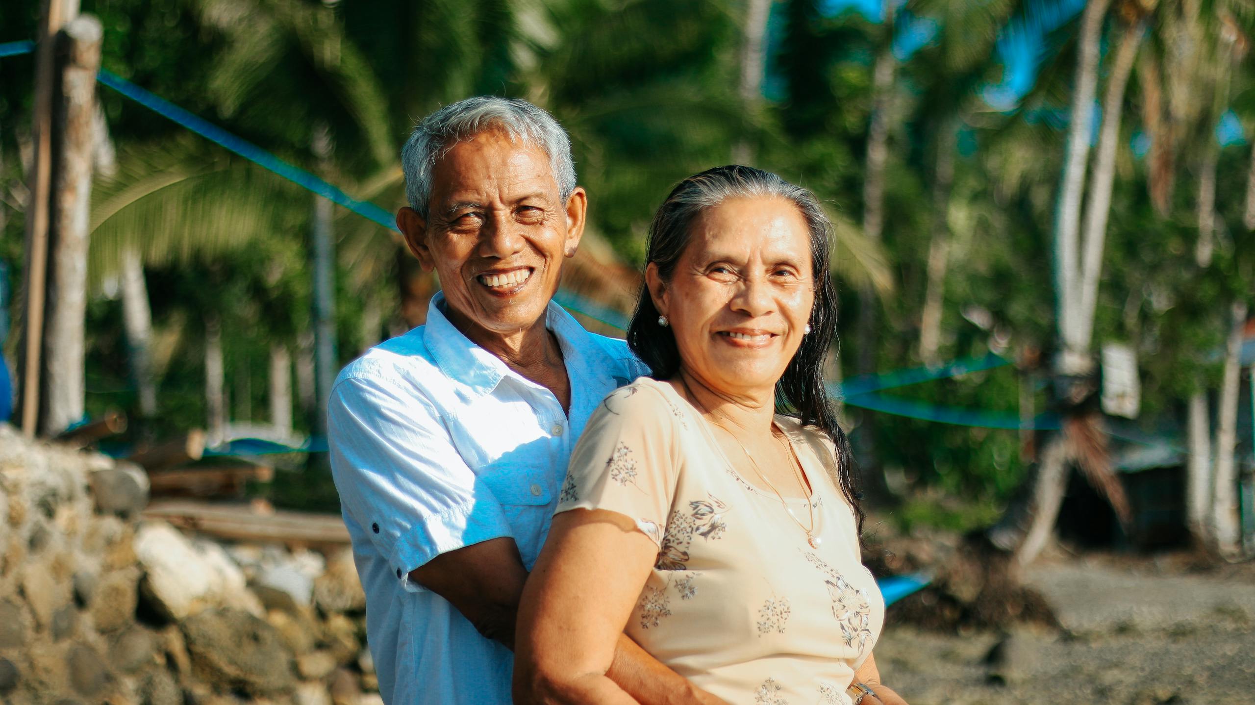 A happy senior couple embracing and smiling at the beach, capturing love and togetherness.