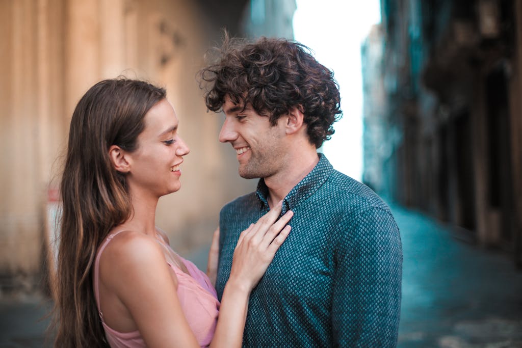 A happy young couple embracing and smiling while enjoying a romantic moment outdoors.